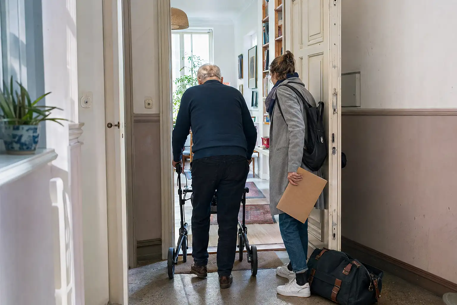 Krankenhausentlassung Checkliste - älterer Mann mit Rollator kehrt mit seiner Tochter in eine Berliner Wohnung zurück - Amor Pflegedienst
