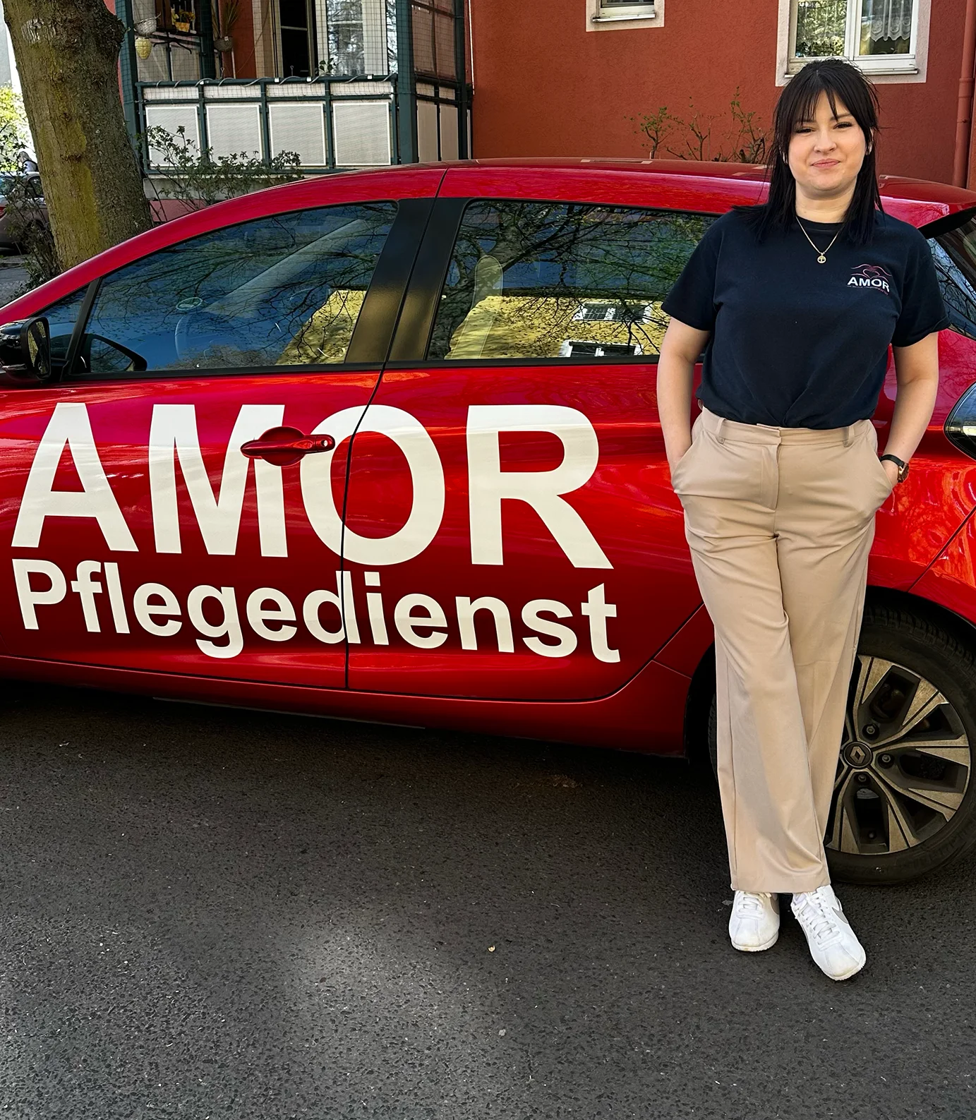 Ambulante Pflege in Berlin - Pflegekraft von Amor Pflegedienst vor dem Dienstfahrzeug in einer Wohnstraße in Berlin-Spandau - Amor Pflegedienst